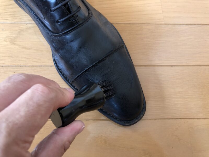 シューキーパーを装着した革靴に黒色のクリームを塗っている様子