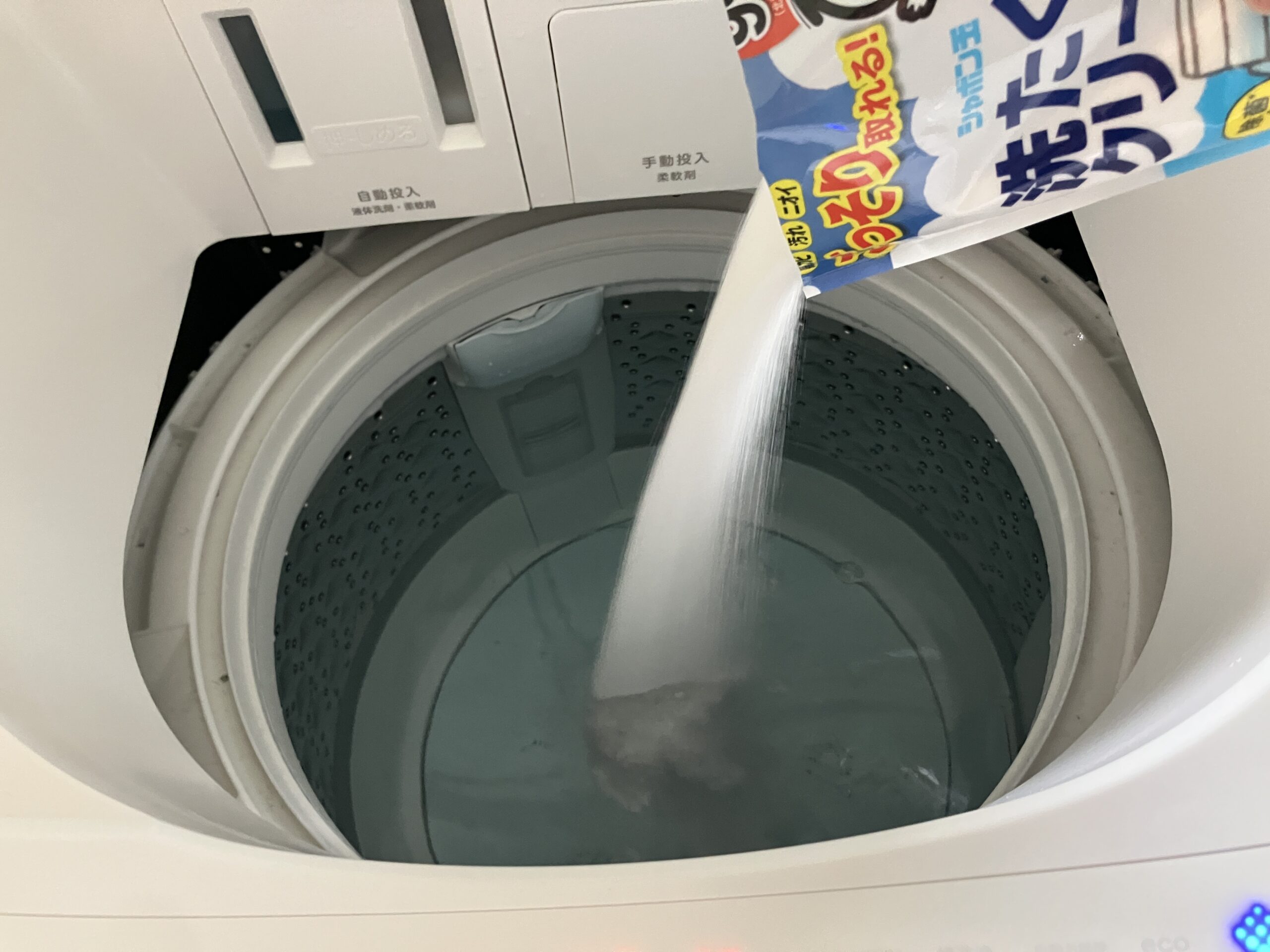 シャボン玉石けん洗たく槽クリーナーの粉末を洗濯機に投入している様子