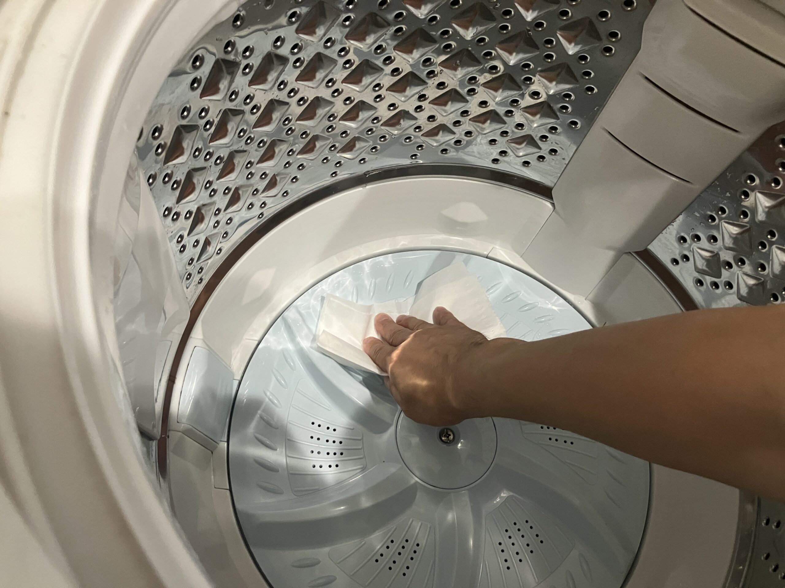 洗濯槽に残った汚れを拭き取って掃除している様子