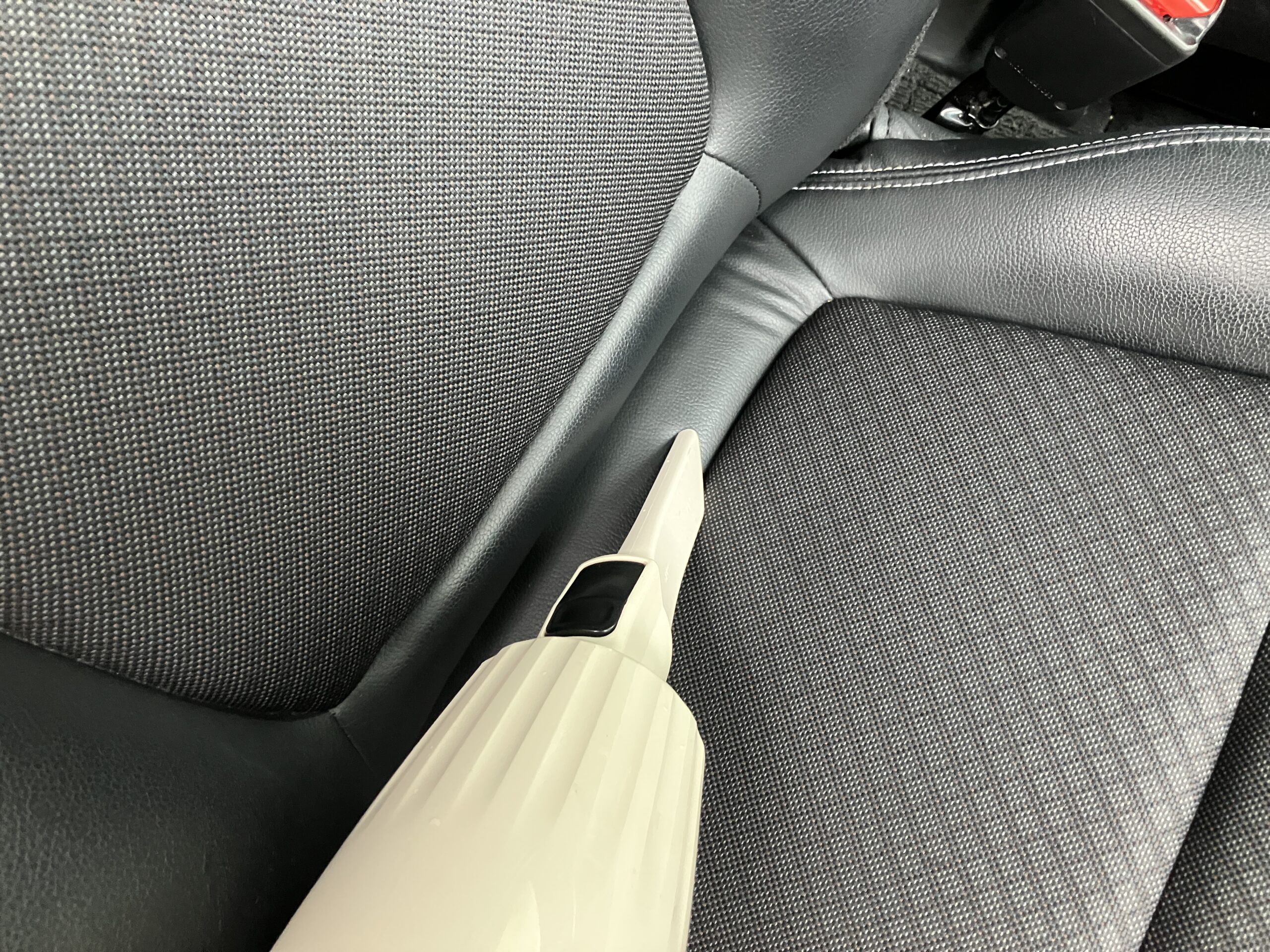マキタCL116DWIのノズルを使って車内の座席の隙間を掃除している様子