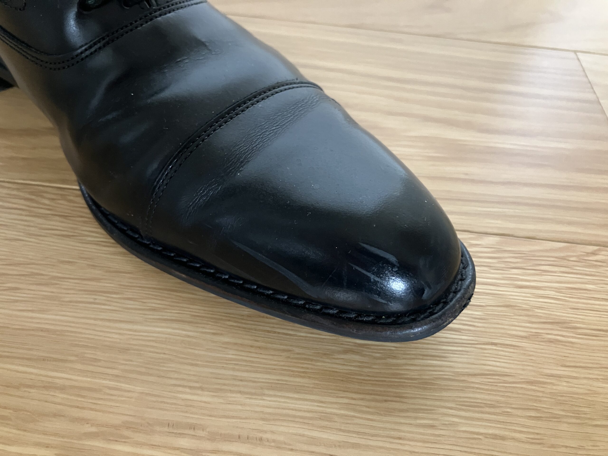 黒い革靴にできた白っぽい擦り傷のクローズアップ