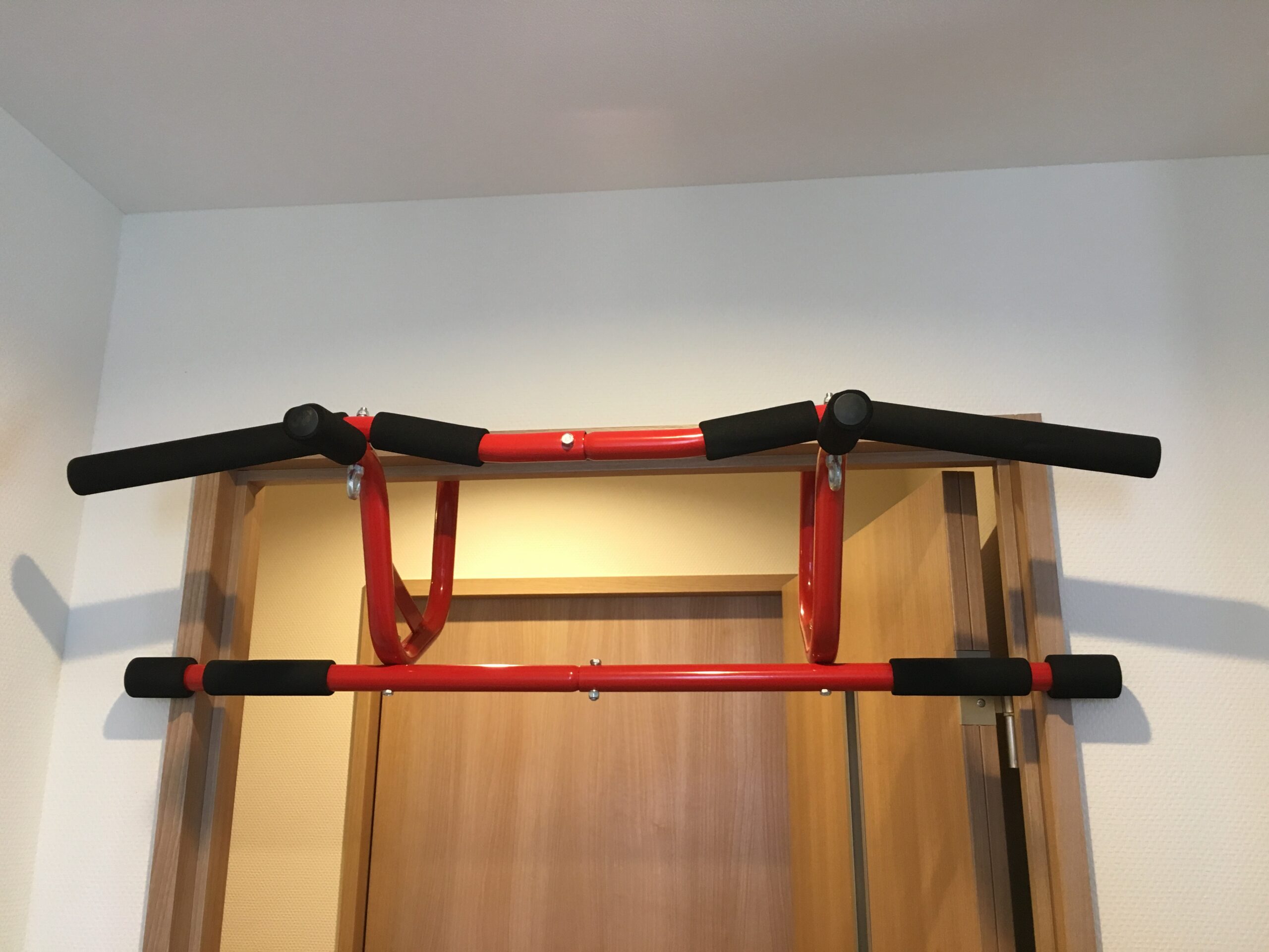 ドア枠の上枠にフックを引っ掛け、横のバーでドア枠を挟んで取り付けた懸垂バーの写真