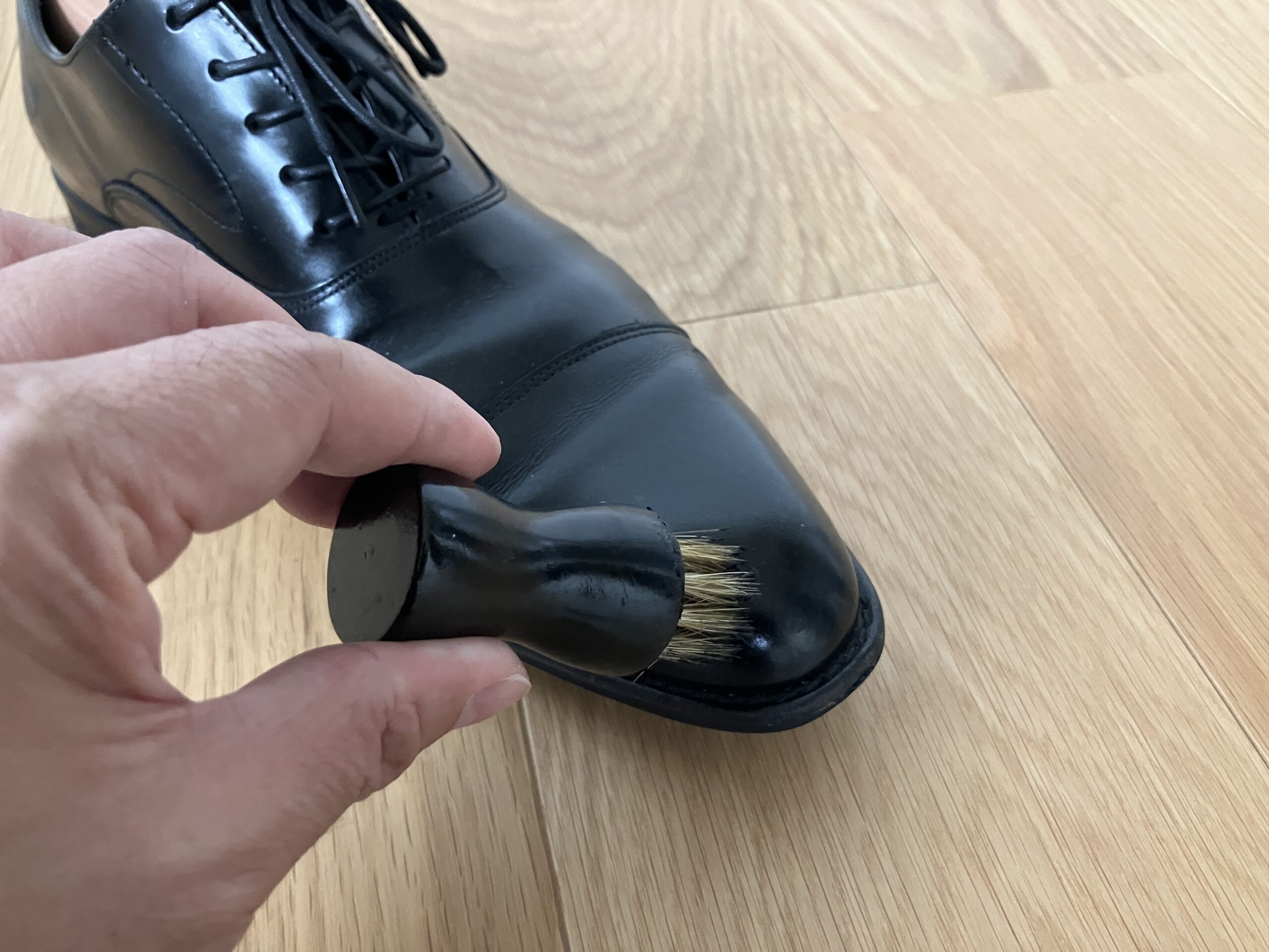 黒い革靴の擦り傷にダブロックスの黒いクリームを塗っている手元